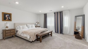 Ein Schlafzimmer mit Bett, Nachttisch, Lampe und Spiegel.
