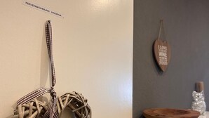 A wicker heart decoration with a heart-shaped keychain on a white door, a wooden sign saying "I love to cook with wine and good food" on the wall, and a wooden bowl on a counter. - FeWo Jagsch - HarzPur - incl. bed linen and towels (Braunlage)