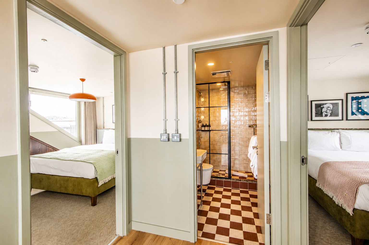 Een hotelkamer met een zwart-wit geruit vloerkleed, een bed, een badkamer met douche en een raam met gordijnen.
