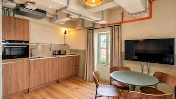 A modern kitchen with wooden cabinets, a built-in oven, and a dining area with a round table and chairs.
