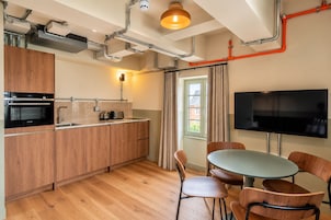 A modern kitchen with wooden cabinets, a built-in oven, and a dining area with a round table and chairs.