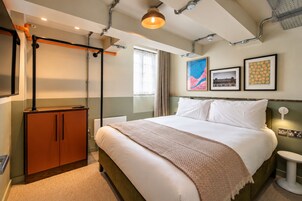 Een hotelkamer met een bed, een kledingkast, een bureau en een raam met gordijnen.