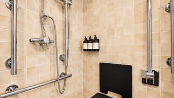 A modern bathroom with beige tiles, a black shower seat, and a set of toiletries on the wall.