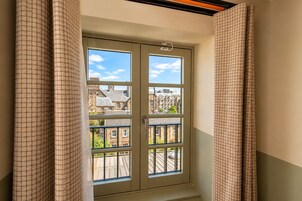 A room with a window overlooking a balcony and a cityscape.