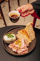 Une assiette avec une tranche de pain, un bol de sauce blanche garnie de verdure et une tranche de jambon.