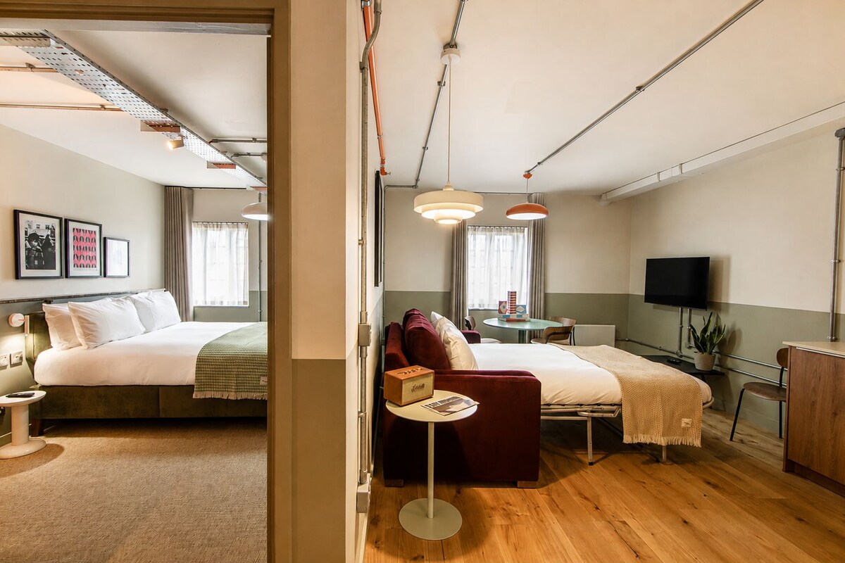 A hotel room with a bed, a desk, a chair, a television, and a window.