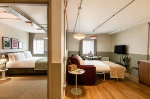 Ein Hotelzimmer mit einem Bett, einem Schreibtisch, einem Sessel, einem Fernseher und einem Fenster.