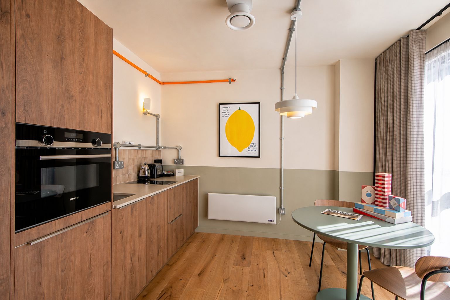 A modern kitchen with a built-in oven, a coffee machine, and a wall-mounted light fixture.