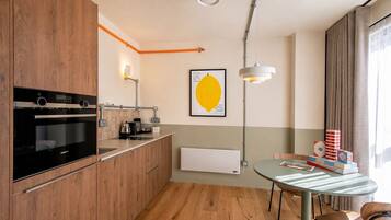 A modern kitchen with a built-in oven, a coffee machine, and a wall-mounted light fixture.