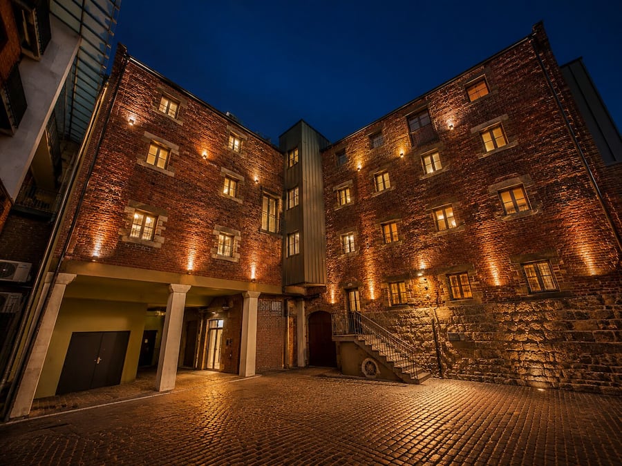 A multi-story building with a brick facade, multiple windows, and a staircase leading to an upper level.