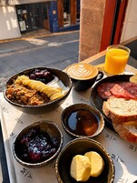 A breakfast tray with various food items, a glass of orange juice, and a cup of coffee with latte art.