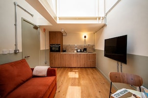 A compact living space with a kitchenette, a sofa, a television, and a chair.