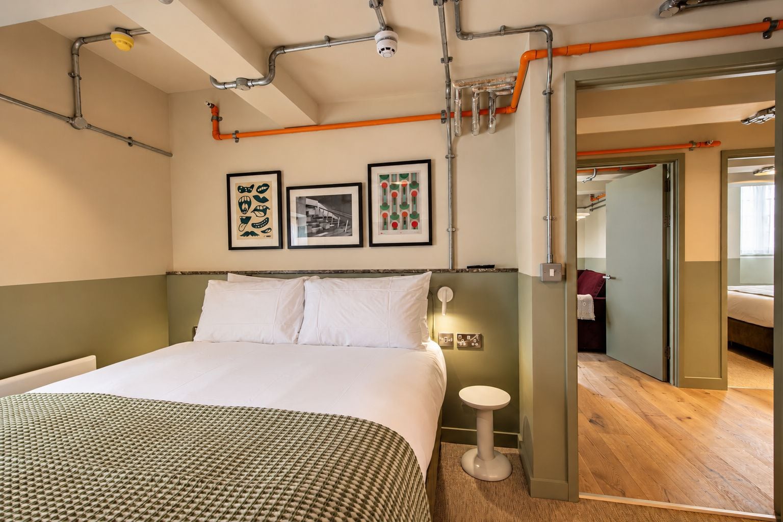A hotel room with a bed, a bedside table, and a wall-mounted light fixture.