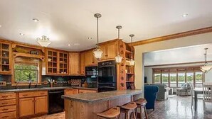 Une cuisine spacieuse avec des meubles en bois, un grand îlot central doté de tabourets et une vue sur un patio extérieur.