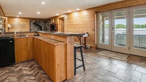 Une cuisine spacieuse dotée de meubles en bois, d’un îlot central et d’une grande porte-fenêtre coulissante donnant sur un espace extérieur.