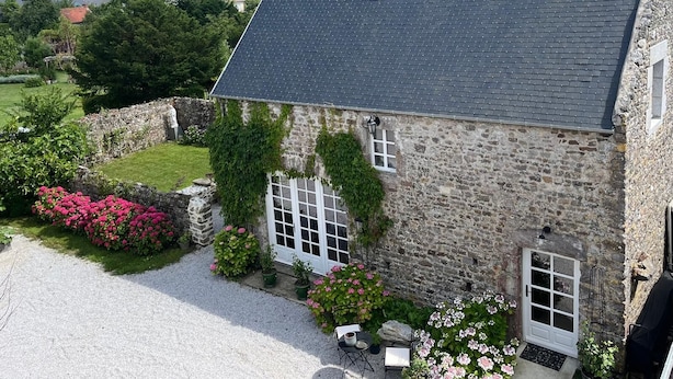 A stone building with a sloped roof, a gravel driveway, and a garden with pink flowers. - A haven of peace just a few minutes from the sea, ideal for families (Montmartin-sur-Mer)