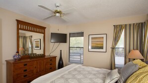 A bedroom with a bed, a dresser, a ceiling fan, a TV, and a window with curtains. - Cozy 1-bedroom condo, in soothing Tucson with fitness room, pools & trails (Tucson)