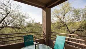 A balcony with a glass table and chairs, overlooking a landscape with sparse trees. - Cozy 1-bedroom condo, in soothing Tucson with fitness room, pools & trails (Tucson)