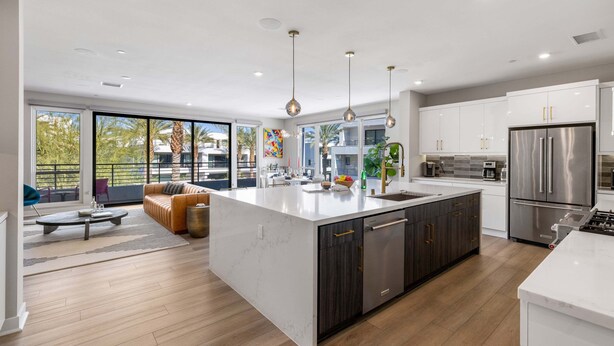 Una cocina moderna con una isla grande, electrodomésticos de acero inoxidable y vistas al exterior.