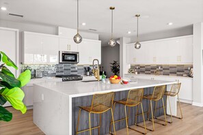 A modern kitchen with white cabinets, a marble island, and gold wire chairs. - Cody Place Luxe–Palm Springs Contemporary Home w/ Resort Amenities, Mountain Views & Downtown Access (Palm Springs)