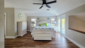 Een slaapkamer met een bed, een kaptafel en een plafondventilator.