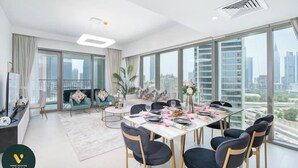 A modern dining area with a large table set for six, surrounded by large windows offering city views. - Vogue | Downtown with Direct Access to Dubai Mall (Dubai)