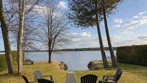 A lakeside seating area with Adirondack chairs and a table, surrounded by trees and a view of the lake. - Comfort by the Aylmer Lake | Evasion du Douze59 (Beaulac-Garthby)
