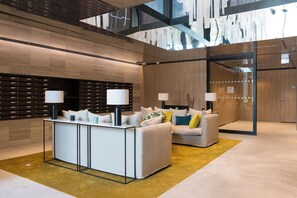 A modern lobby with a reception desk, sofas, and a glass wall. - Zenao Appart'hôtels Auteuil (Paris)