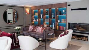 A modern living room with a sofa, two white armchairs, a coffee table, and a fireplace. - Zenao Appart'hôtels Auteuil (Paris)