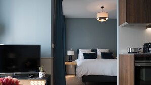 A hotel room with a bed, a TV, a coffee maker, a lamp, and a small table with a cactus. - Zenao Appart'hôtels Auteuil (Paris)