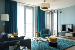 Un salon moderne comprenant un canapé, un fauteuil, une table basse et un téléviseur.