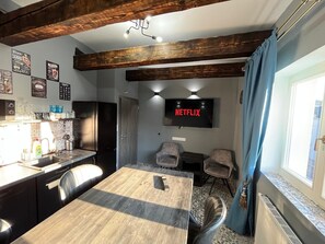 A compact living space with a kitchen, dining area, and a TV displaying 'NETFLIX'. - Modern Wood Loft | 7 Min to Colonnade (Karlovy Vary)