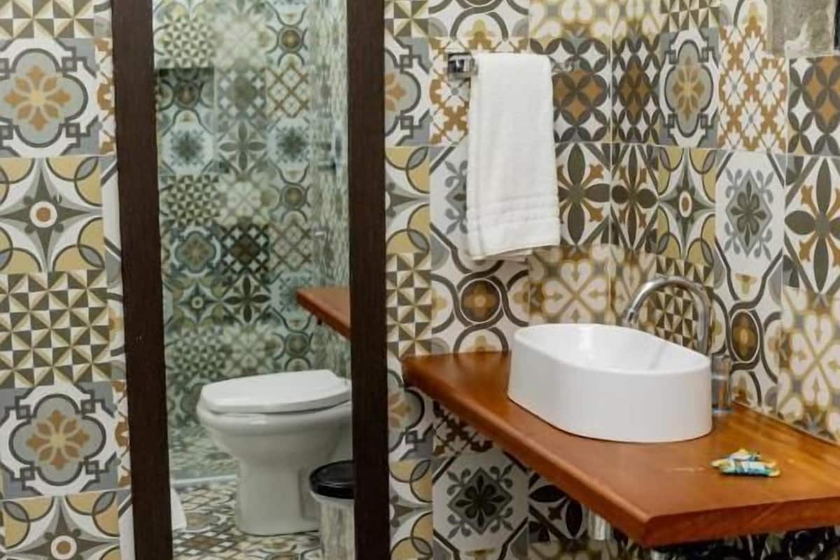 A bathroom with patterned tiles, a wooden vanity with a sink, a mirror, and a toilet.