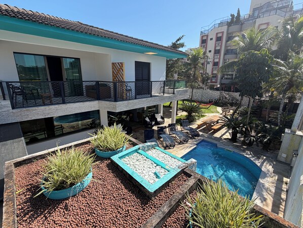A modern two-story building with a rooftop terrace, a swimming pool, and outdoor seating.