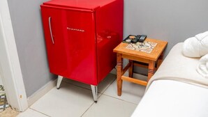 Un meuble rouge avec une poignée, une petite table en bois dont le plateau est orné d’un motif, et un canapé blanc.
