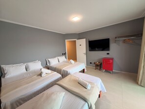 A hotel room with two beds, a television mounted on the wall, and a red cabinet. - Santa Rita Pousada (Guarujá)