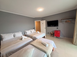 Camera d'albergo con due letti, una televisione a parete e un armadietto rosso.