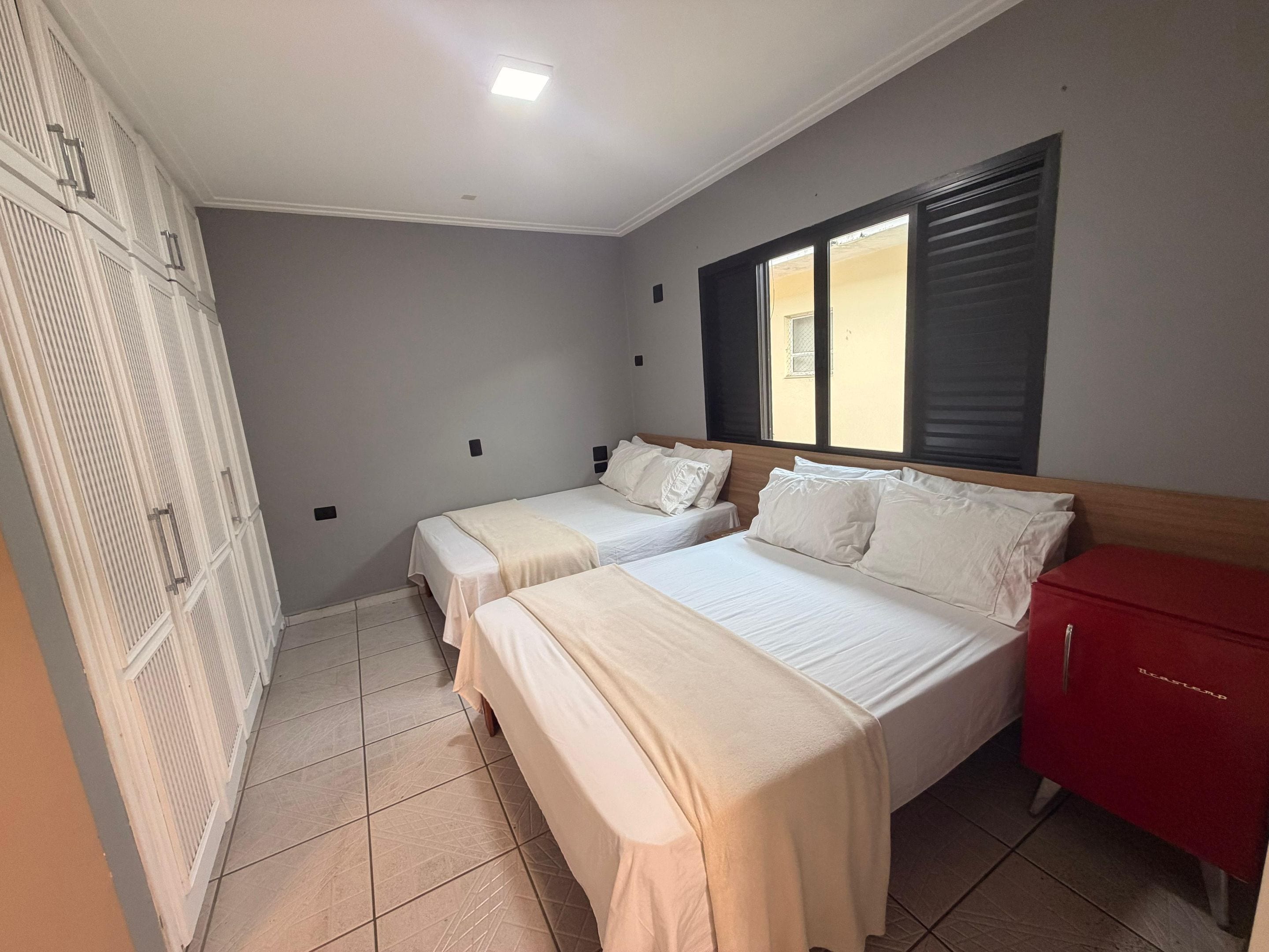 Ein Hotelzimmer mit zwei Betten, einem roten Schrank und einem Fenster mit Jalousien.