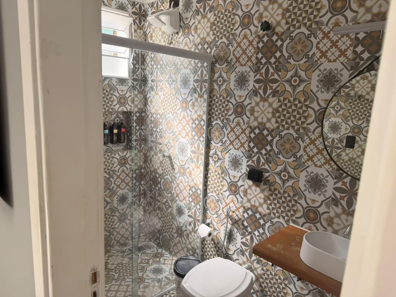 A bathroom with patterned tiles, a glass shower enclosure, a toilet, and a sink.