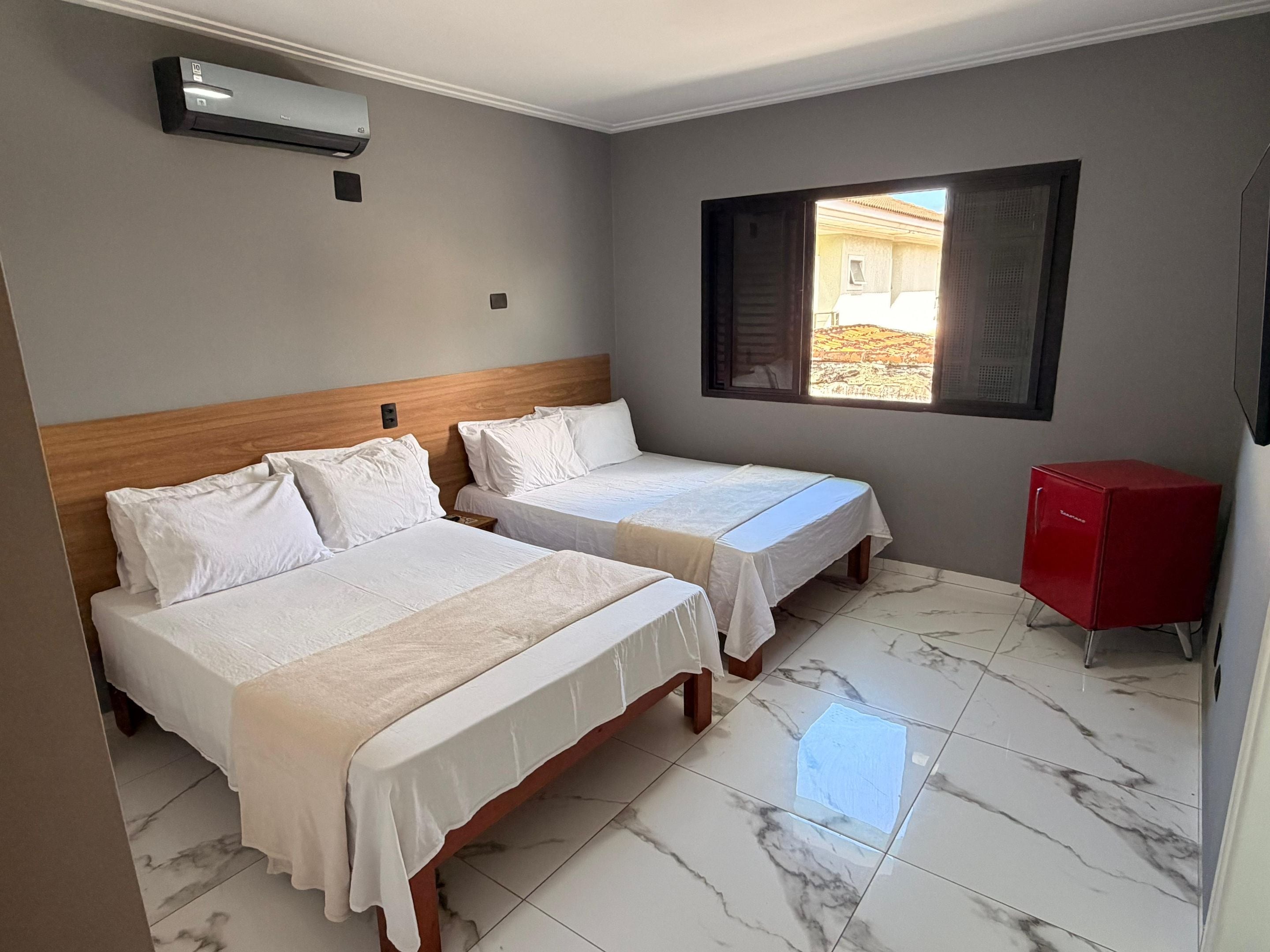 Una habitación de hotel con dos camas, un armario rojo y una ventana con vistas.