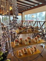 A restaurant with wooden tables and chairs, a hanging decoration, and a view of the outdoors.
