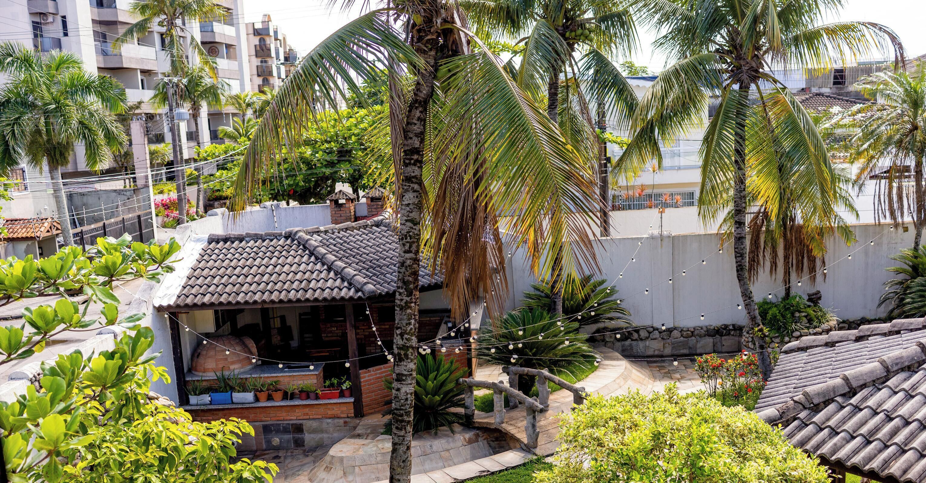 A residential area with a house featuring a tiled roof, a small porch with potted plants, and a string of lights.