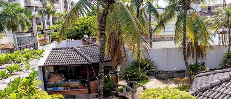A residential area with a house featuring a tiled roof, a small porch with potted plants, and a string of lights.