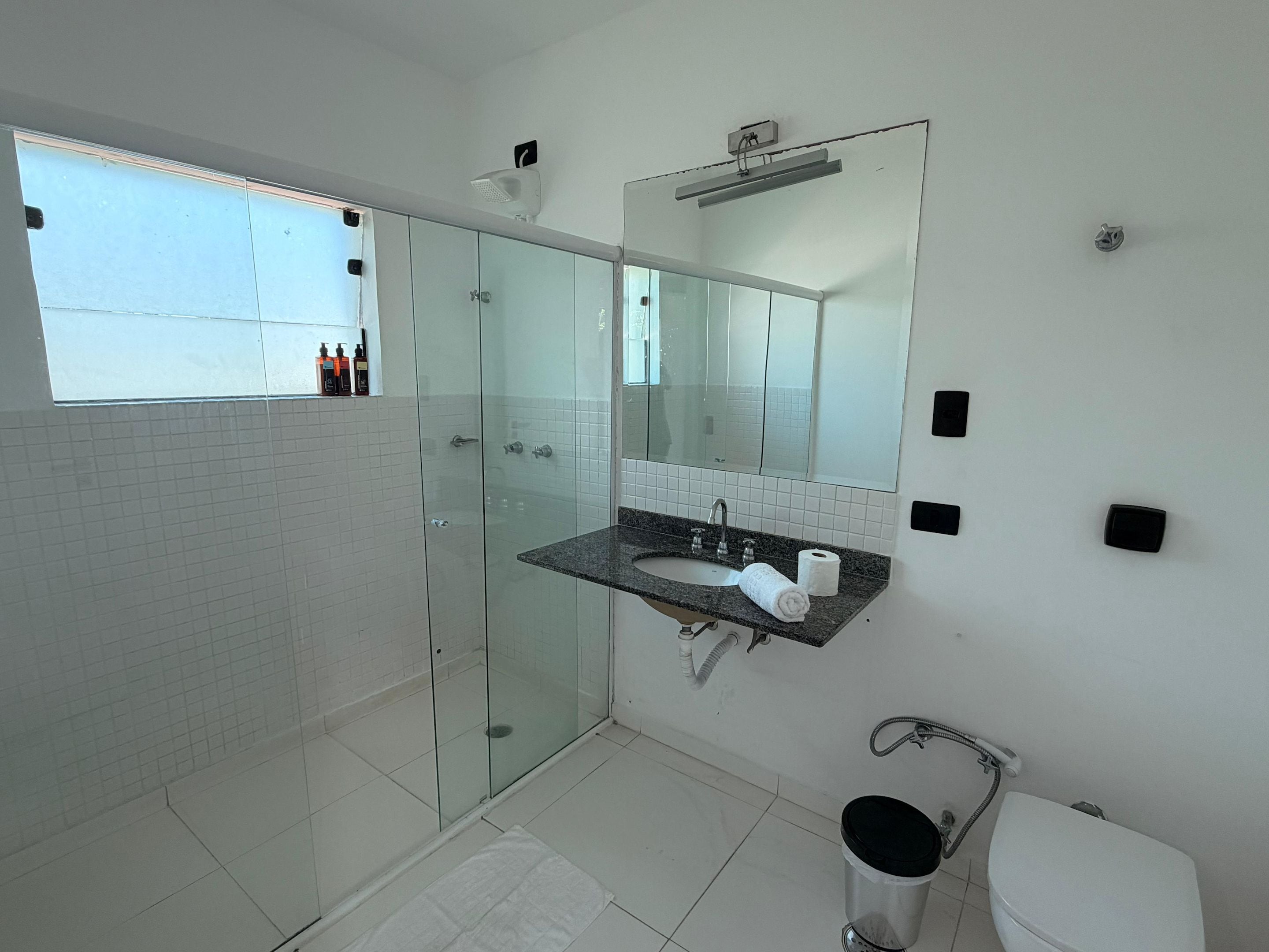 A modern bathroom with a glass shower enclosure, a sink with a marble countertop, and a toilet.