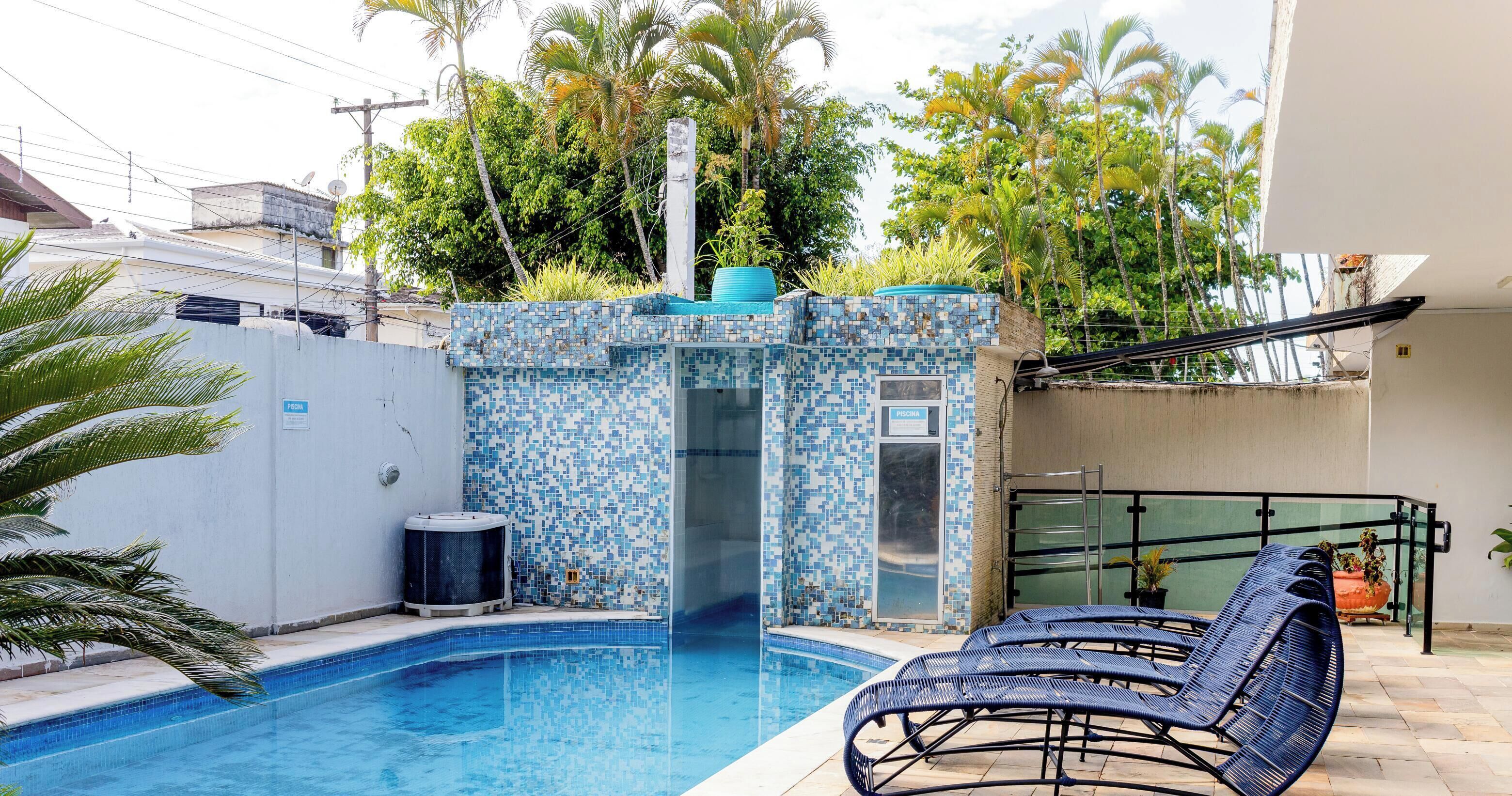 A swimming pool with a mosaic tile wall, a hot tub, and lounge chairs.