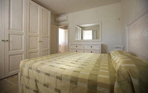 Un dormitorio con cama, cómoda, espejo y armario.