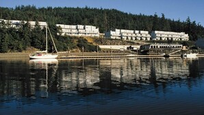 Ein Ufergrundstück mit einer Marina, einer angossenen Segelyacht und einem mehrstöckigen Gebäude mit Balkonen mit Blick auf das Wasser.