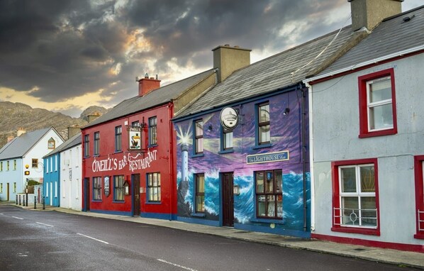 A row of colorful buildings with signs for 'O'Neill's Bar & Restaurant' and 'The Lighthouse Inn'.