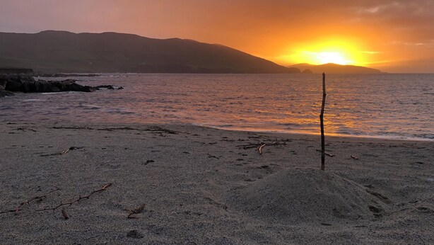 A beach with a sunset, rocky shoreline, and a stick in the sand. - Mountain Retreat situated amongst the ruins of the old miners village (Allihies)