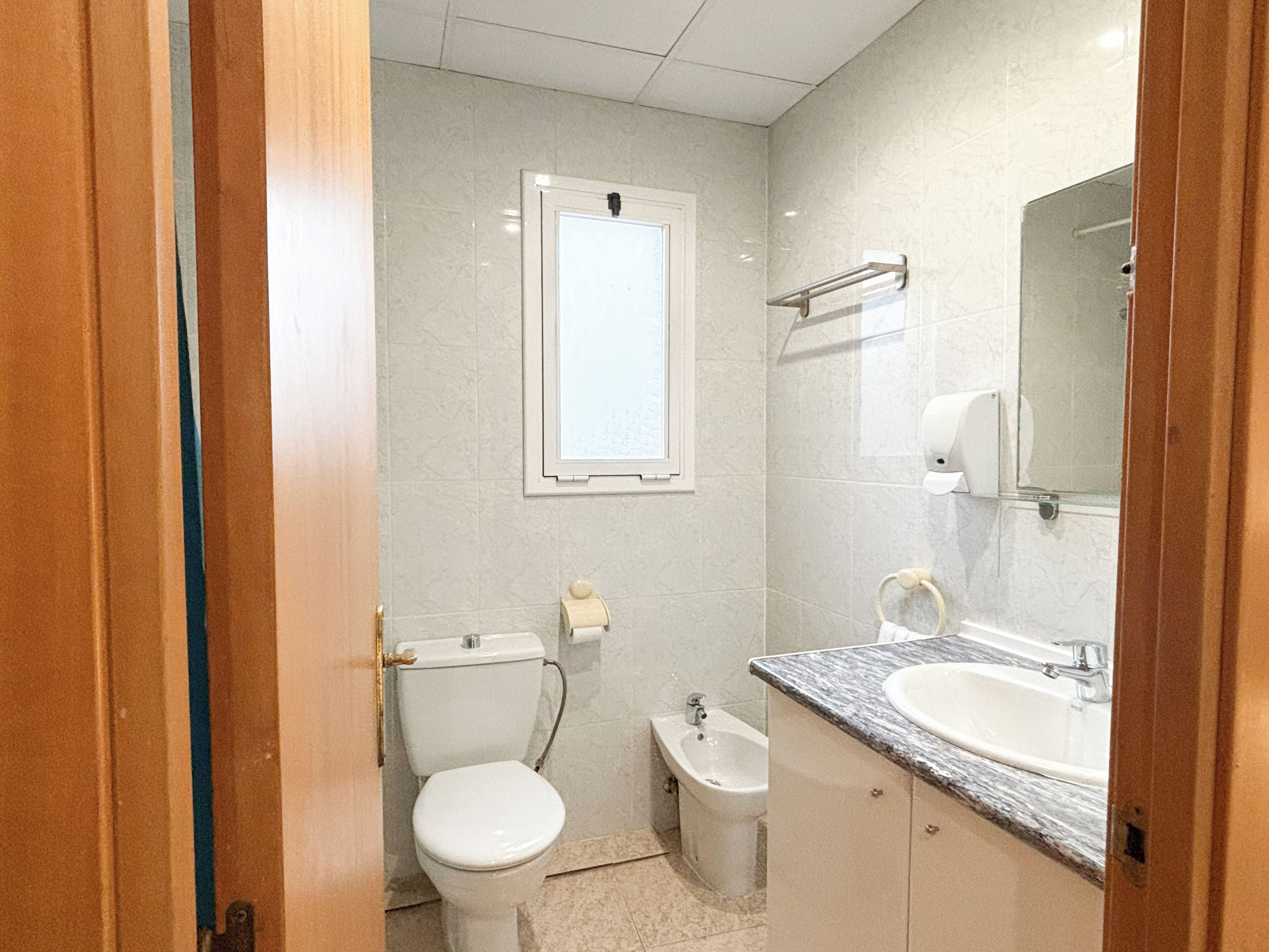 Un baño pequeño con inodoro, bidé y lavabo con espejo.